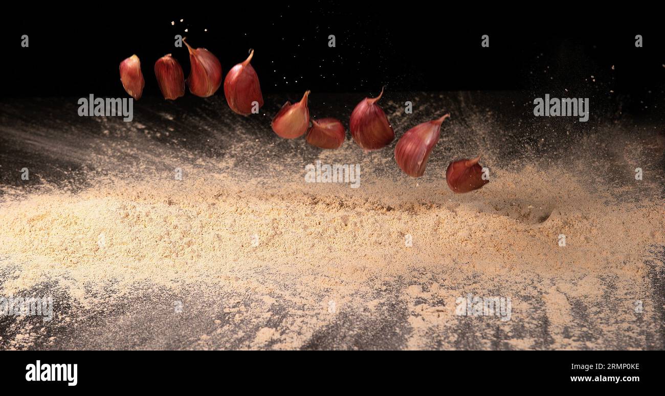 Garlic, allium savitum, Garlic pawns Falling on Garlic Powder on Black ...