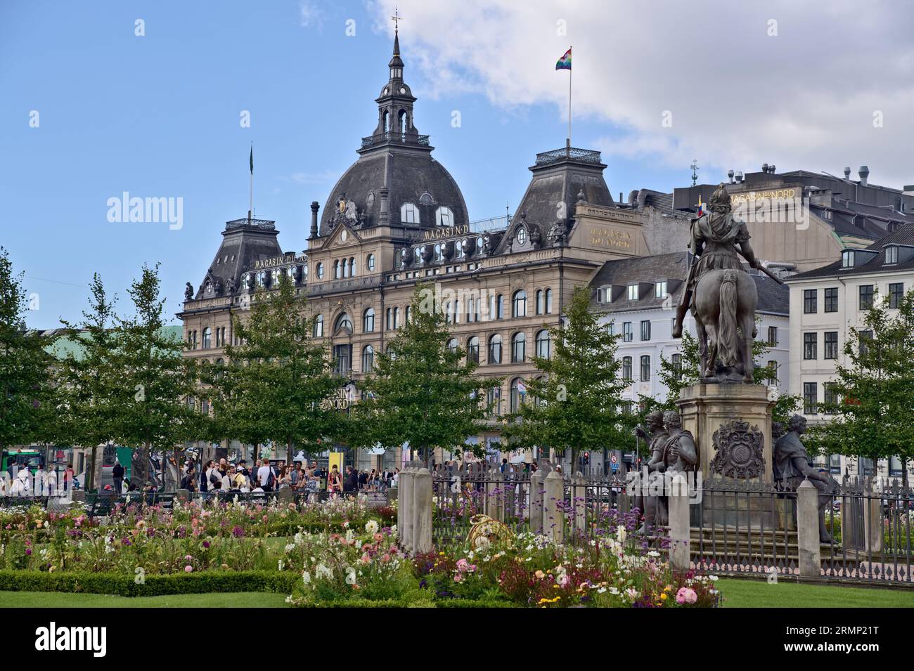 View from the Kings New square on the bronze equestrian statue of Christian V and the Magasin du Nord building with LGBTQ flag , Copenhagen Denmark Stock Photo