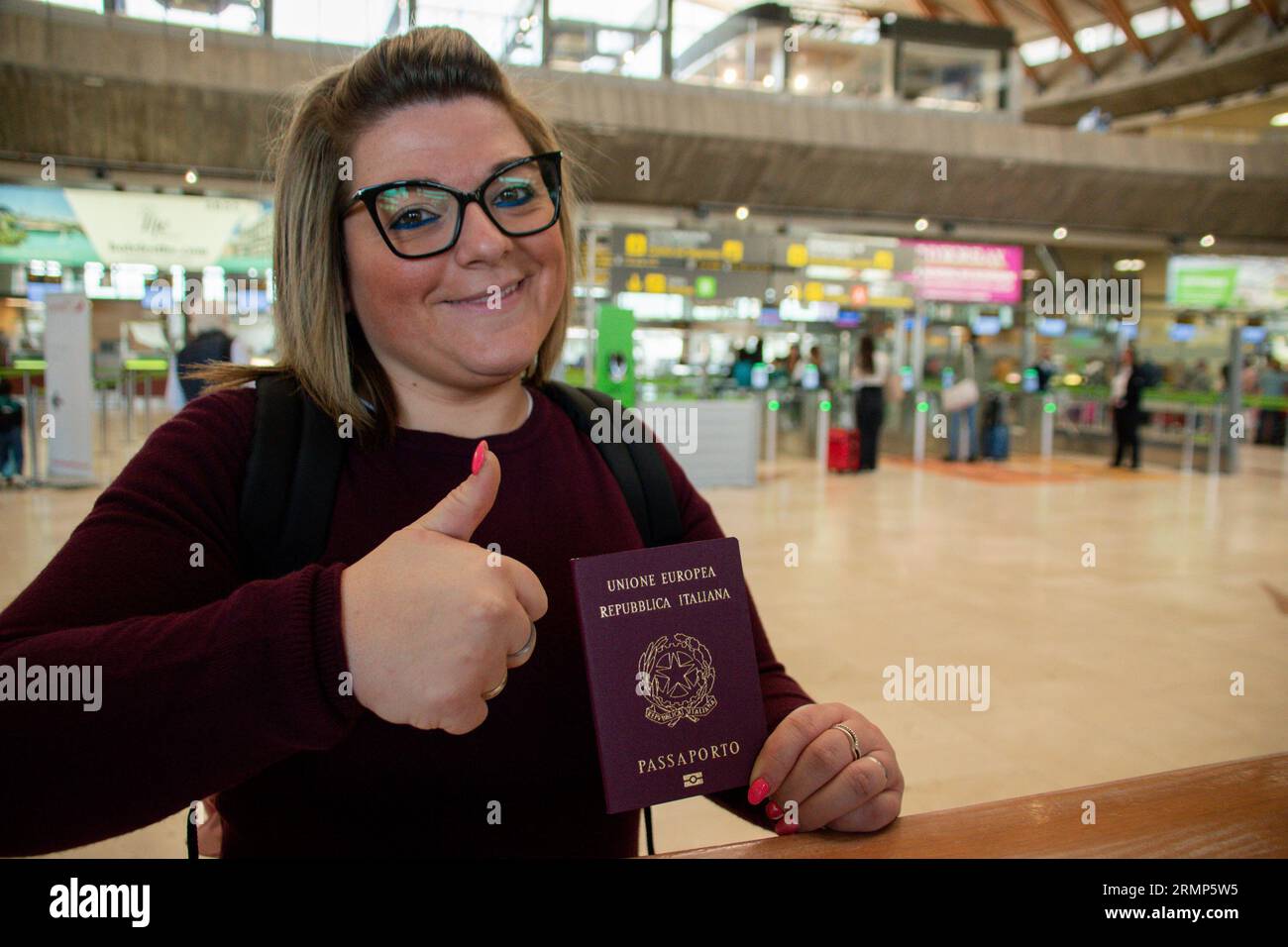 Thumbs up of an Italian female passenger showing her passport at the airport before leave Stock Photo