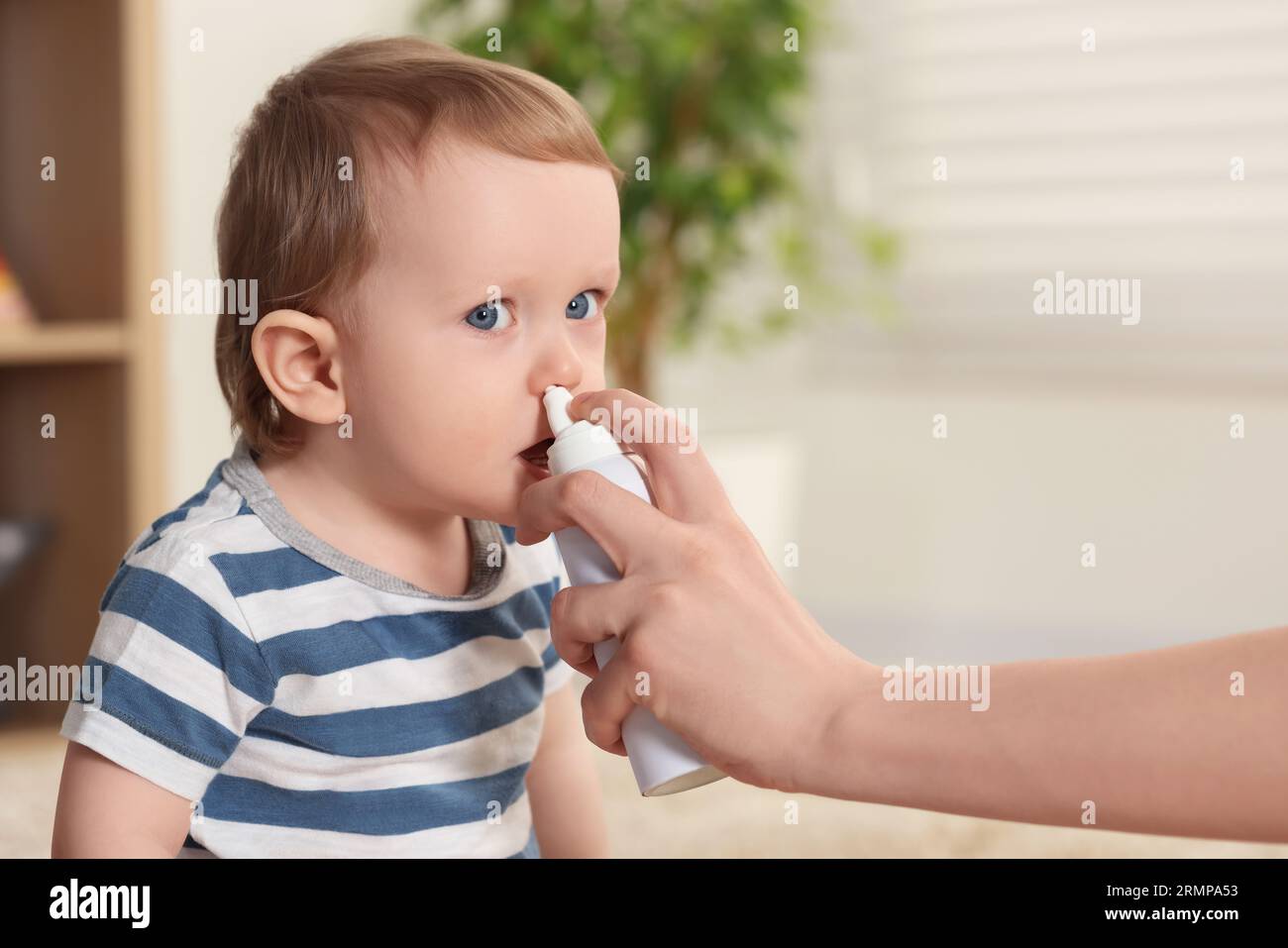 Mother helping her baby to use nasal spray indoors Stock Photo Alamy