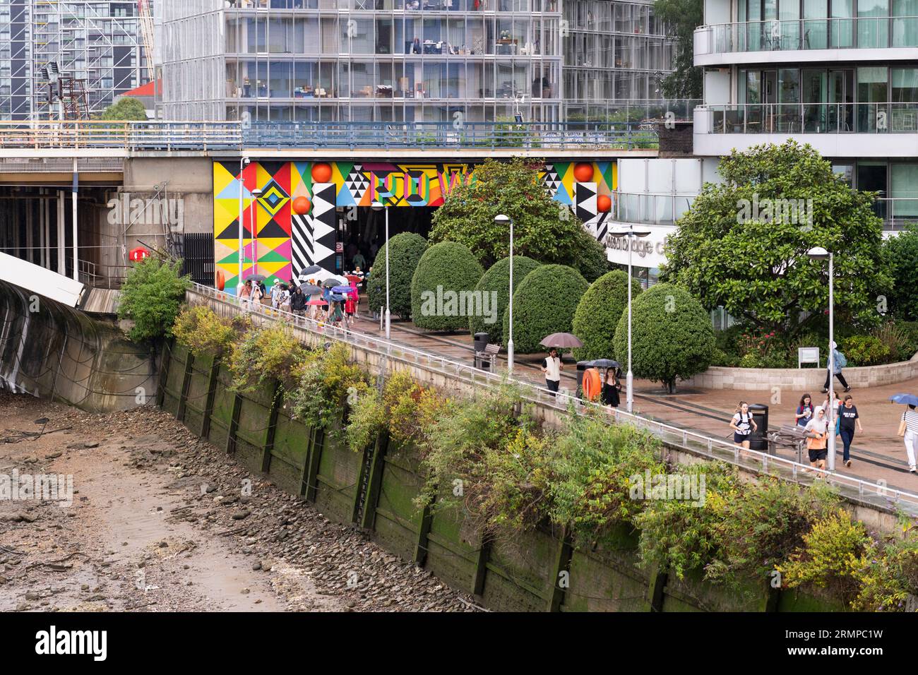People walking through the Grosvenor Arch Entrance under the Grosvenor Railway Bridge to Battersea Power Station on a rainy day in London. England Stock Photo