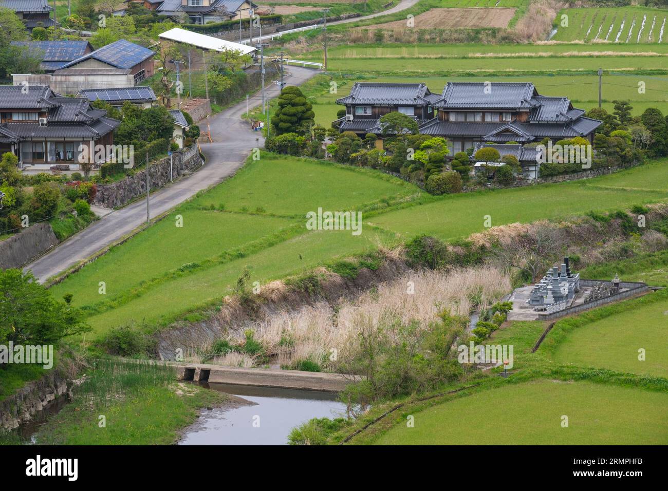 Japan, Kyushu. View of Farmland by Tashibu-no-sho Village, Kunisaki Peninsula, Oita Prefecture. Rice Paddies not yet Planted. Village Cemetery on righ Stock Photo