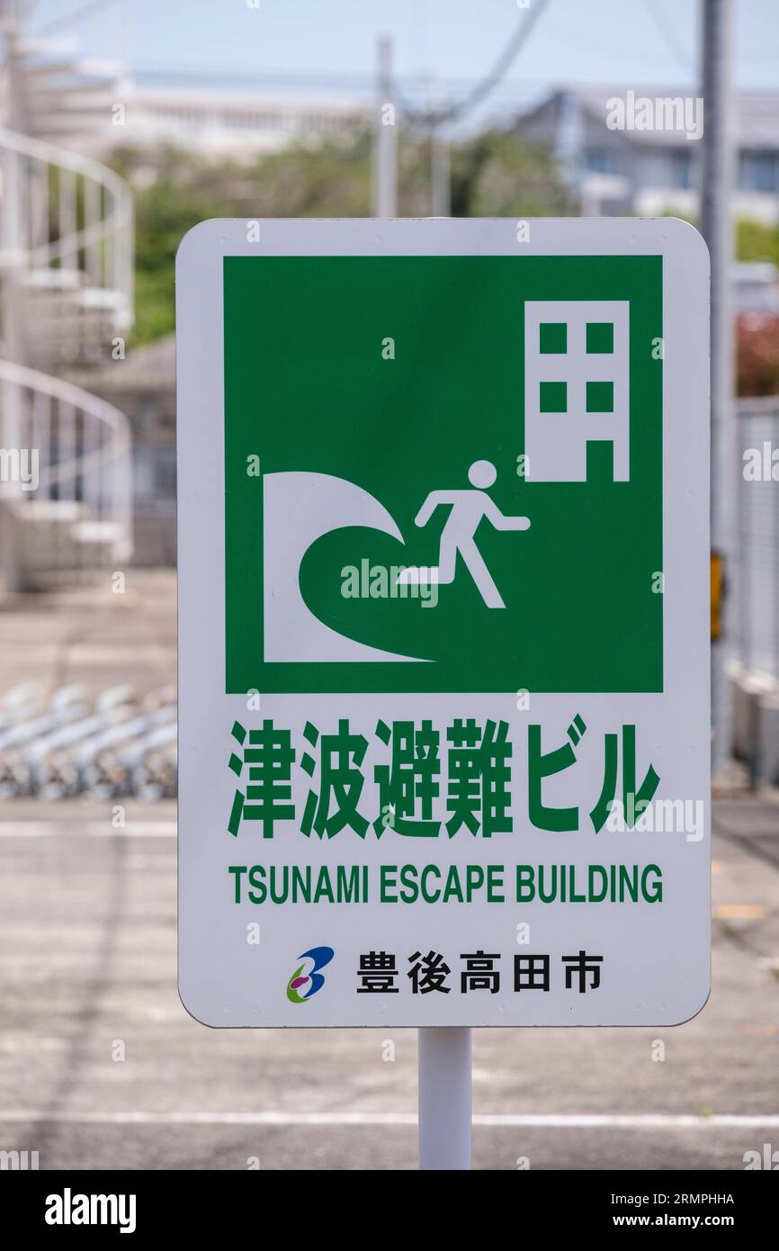 Japan, Kyushu.Bungo-takada Street Scene. Sign Warning of Tsunami Threat, Circular Stairway in background offers quick escape to higher elevation. Stock Photo