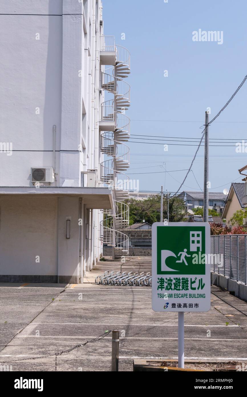 Japan, Kyushu.Bungo-takada Street Scene. Sign Warning of Tsunami Threat, Circular Stairway in background offers quick escape to higher elevation. Stock Photo