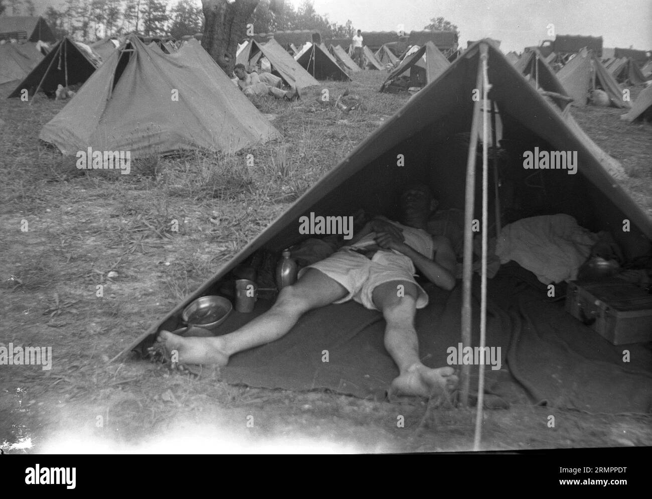 Soldier sleeping in army tent at tent camp. Members of the United States Army’s 114th infantry division train to fight against Germany in Europe during WWII. Stock Photo
