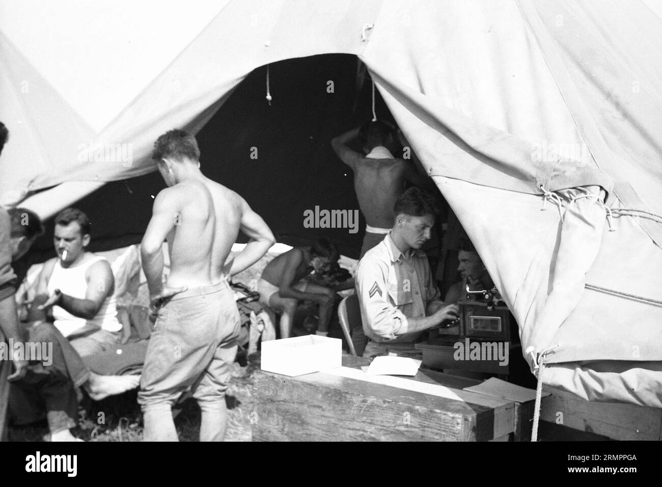 Soldier typing inside tent. Members of the United States Army’s 114th infantry division train to fight against Germany in Europe during WWII. Stock Photo