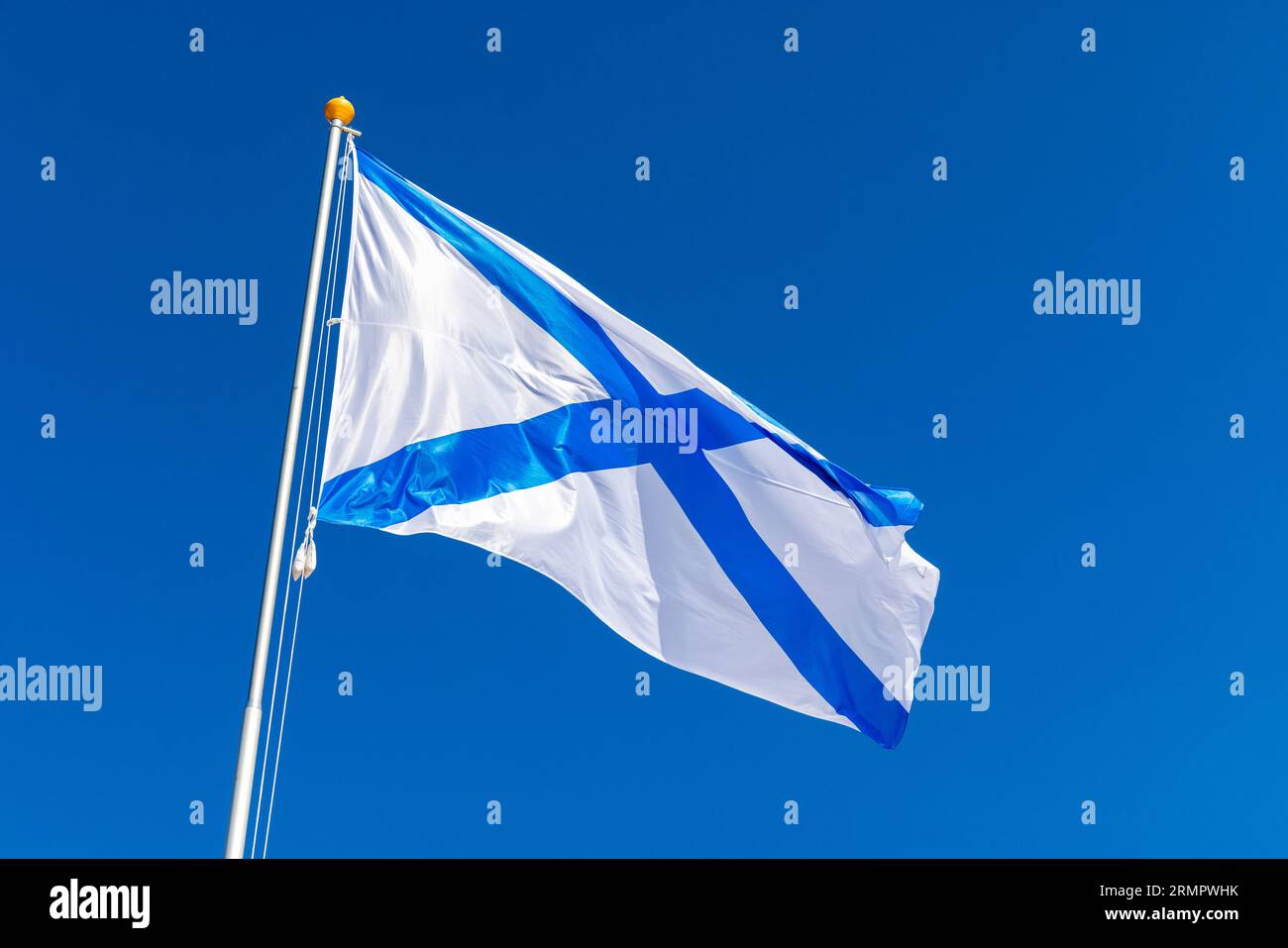 Ensign of the Russian Navy is under blue sky, also known as the St. Andrews flag. This is the stern flag of the ships of the Russian Imperial Navy and Stock Photo