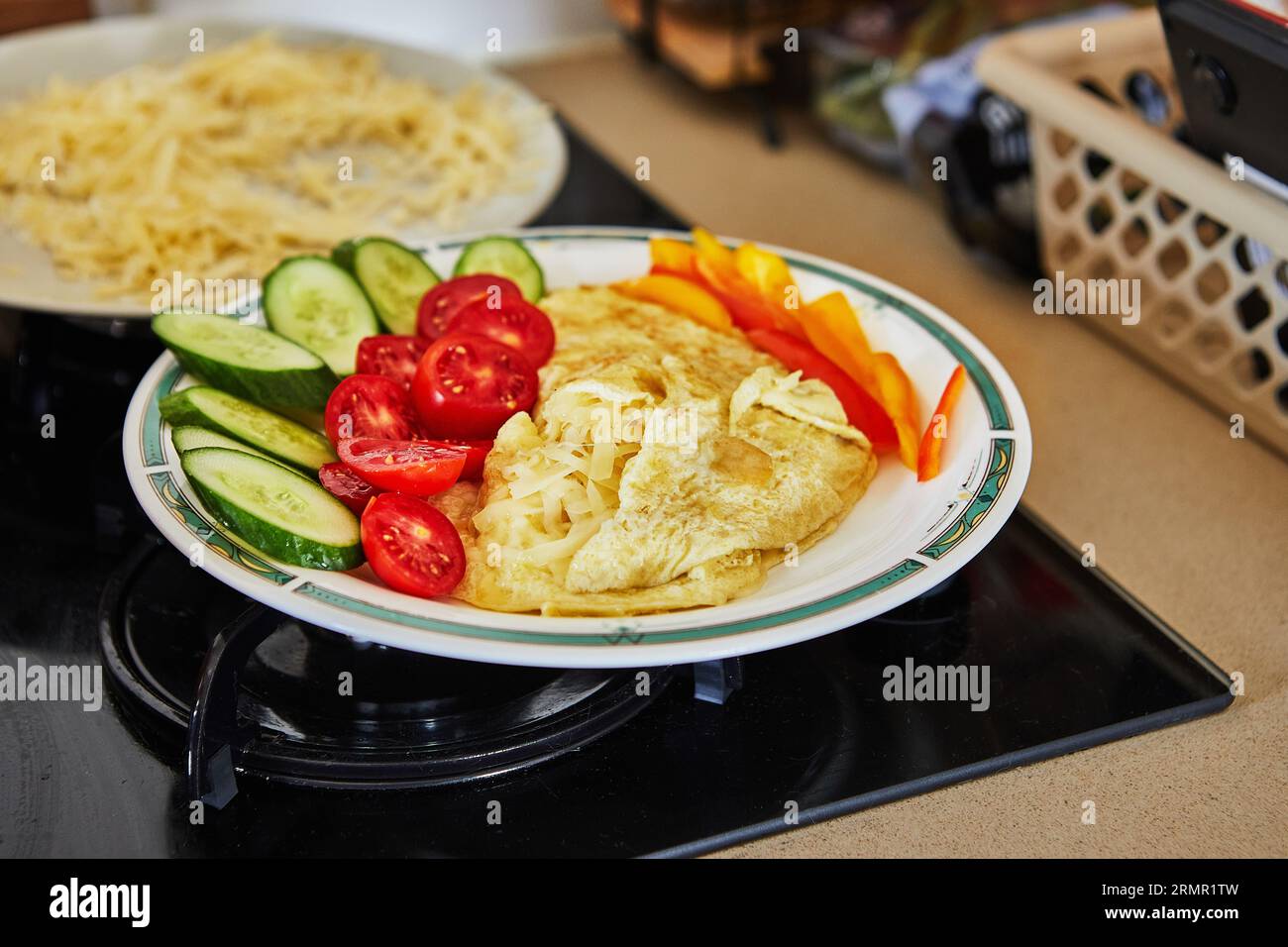 Morning healthy breakfast of scrambled eggs with parmesan cheese, cucumbers, cherry tomatoes and bell peppers in home kitchen Stock Photo