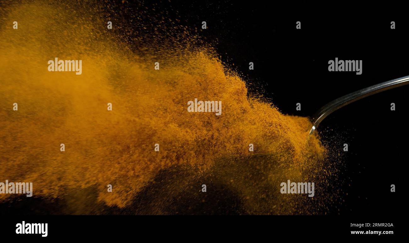 Spoon and Curry Powder falling from Spoon against Black Background ...