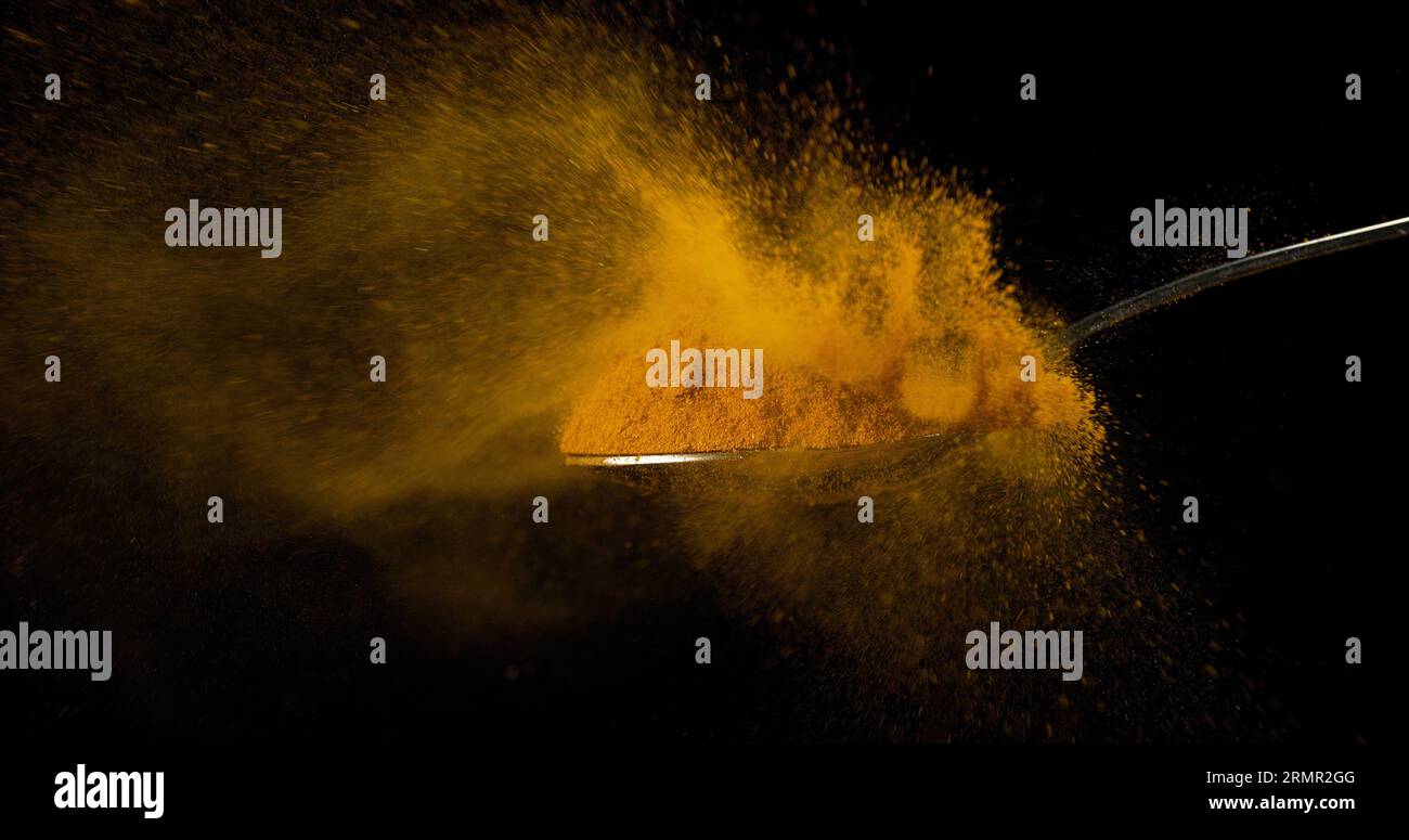 Powder Fallin Spoon and Curry Powder falling from Spoon against Black Background ...