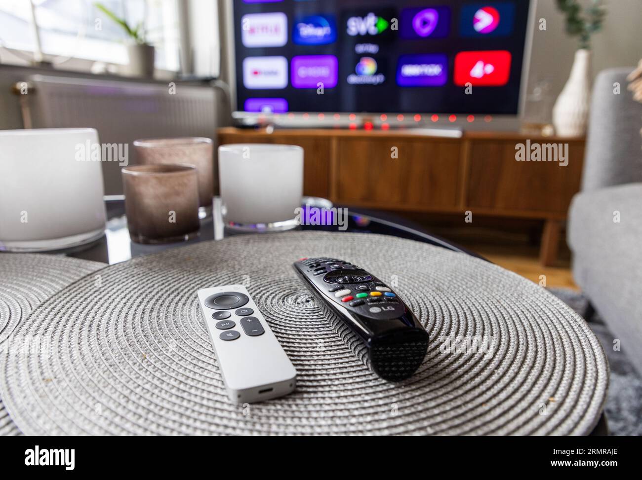 Remote controls in front of a tv screen in a home. Stock Photo