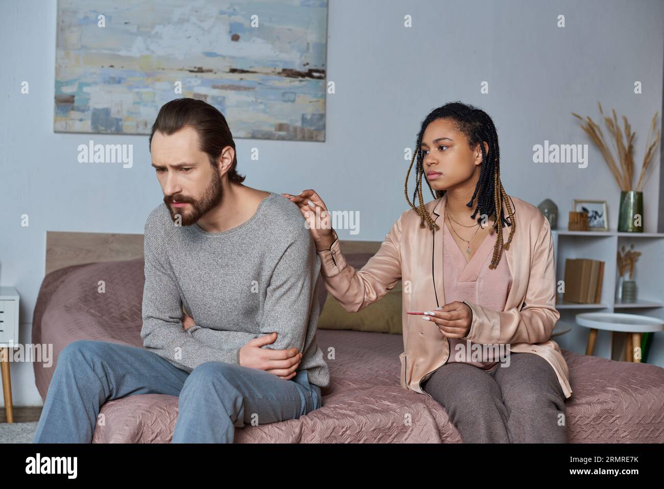 abortion concept, african american woman calming stressed man, bedroom, pregnancy test, unexpected Stock Photo