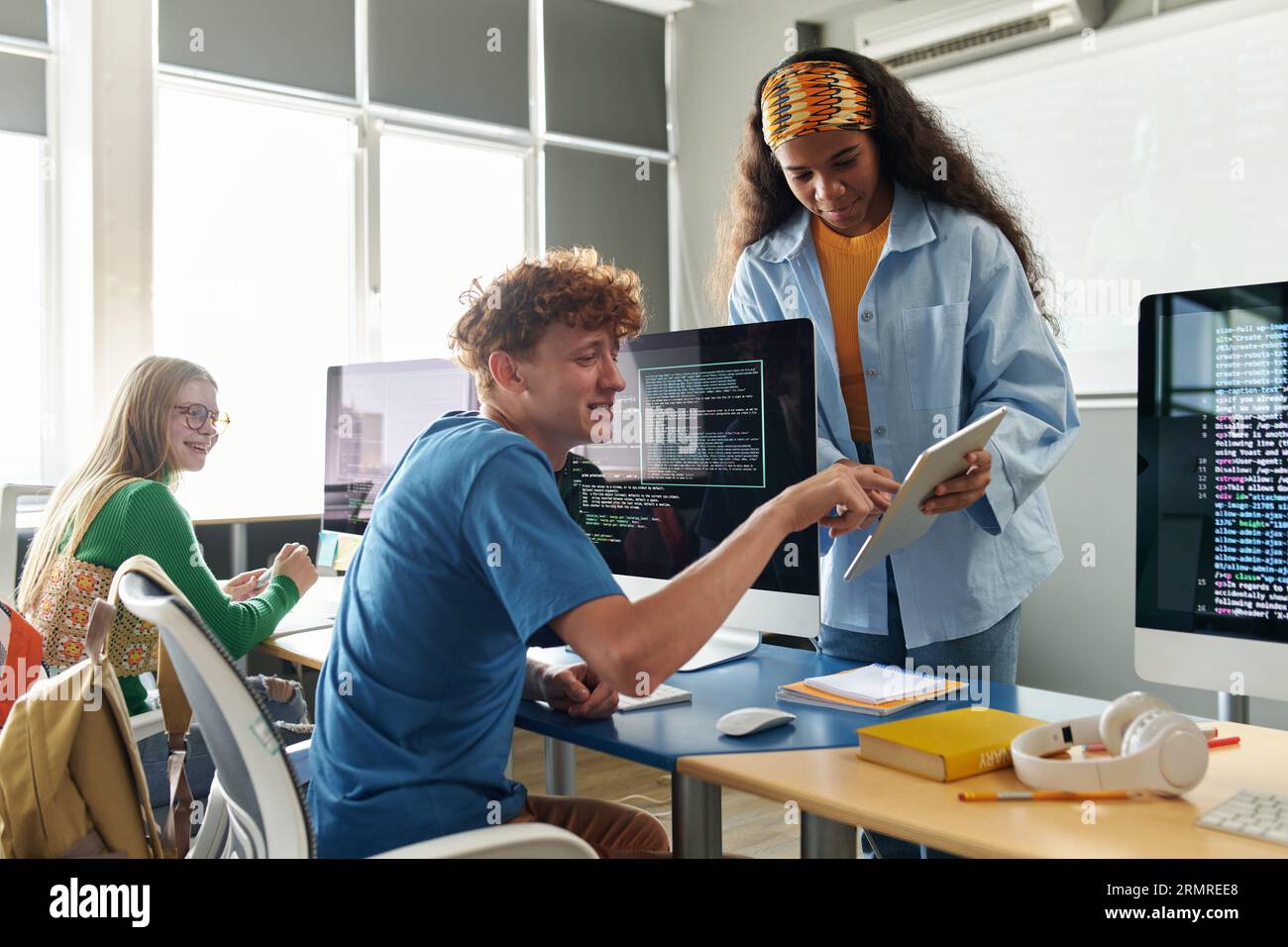 Students using tablet pc and discussing computer program together during IT lesson Stock Photo
