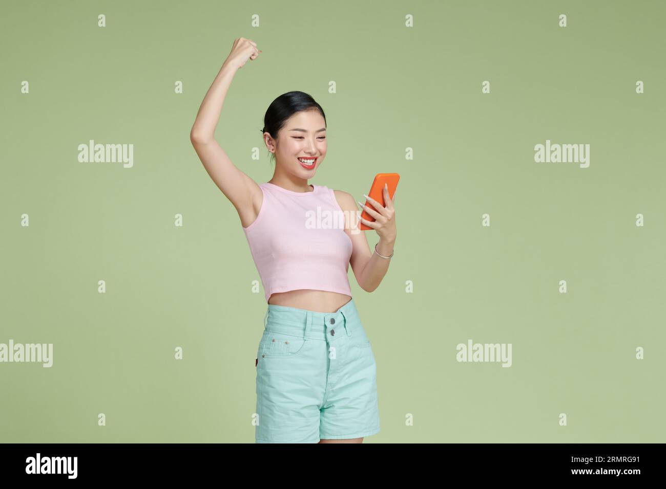 Happy Asian woman holding a smartphone and winning the prize. Stock Photo