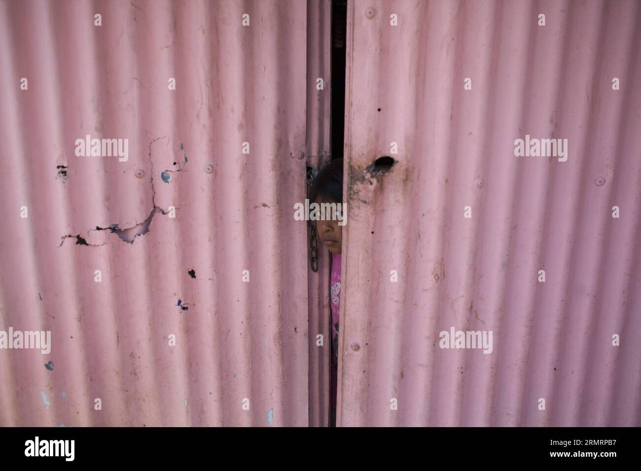 GUATEMALA CITY, July 30, 2014 -- A girl peeks from her house during an eviction conducted by the National Civil Police of Guatemala, in the settlement Linda Vista, in Guatemala City, capital of Guatemala, on July 30, 2014. Approximately 150 families from the Linda Vista settlement were evicted from the lands they have occupied for the last 18 months. ) (jp) (ah) GUATEMALA-GUATEMALA CITY-SOCIETY-EVICTION LuisxEcheverria PUBLICATIONxNOTxINxCHN   Guatemala City July 30 2014 a Girl Peeks from her House during to Eviction conducted by The National Civil Police of Guatemala in The Settlement Linda V Stock Photo