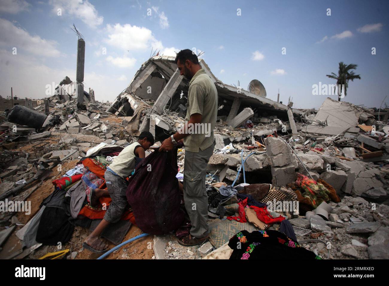 (140805) -- GAZA, Aug. 5, 2014 -- Palestinians collect belongings from their destroyed house after it was hit by an Israeli strike, in Khuzaa village, east of Khan Younis, in the southern Gaza Strip, on Aug. 5, 2014. A 72-hour ceasefire in the Gaza Strip brokered by Egypt came into effect at 8:00 a.m. local time (0500 GMT) on Tuesday, marking the latest attempt to stop the Israeli-Palestinian clashes after previous efforts ended in failure. ) MIDEAST-GAZA-CEASEFIRE YasserxQudih PUBLICATIONxNOTxINxCHN   Gaza Aug 5 2014 PALESTINIANS Collect belonging from their destroyed House After IT what Hit Stock Photo