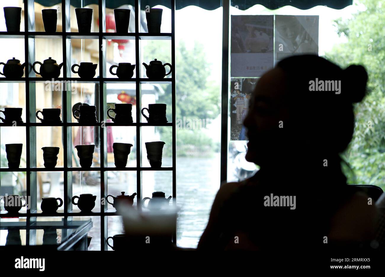 (140806) -- BEIJING, Aug. 6, 2014 -- Zhang Lingyun waits for a fellow ceramic artist at a cafe in Jingdezhen, east China s Jiangxi Province, July 17, 2014. Zhang Lingyun is 40. It s been 20 years since the ceramic artist came to Jingdezhen, China s porcelain capital . Zhang s story with ceramics had a random, romantic start: she knew barely anything about ceramics before she came across the name Jingdezhen Ceramic Institute (JCI) when applying for college. Ceramics sounded interesting so I filed the application for JCI. The whim of impulse had made great difference in Zhang s life. Her very fi Stock Photo