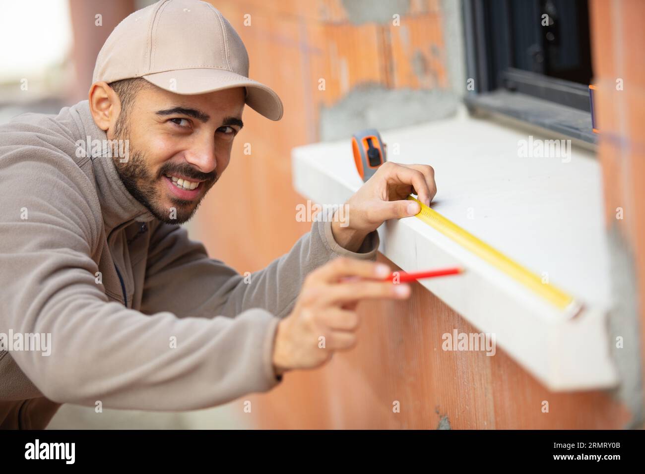 man in a blue shirt does window installation Stock Photo