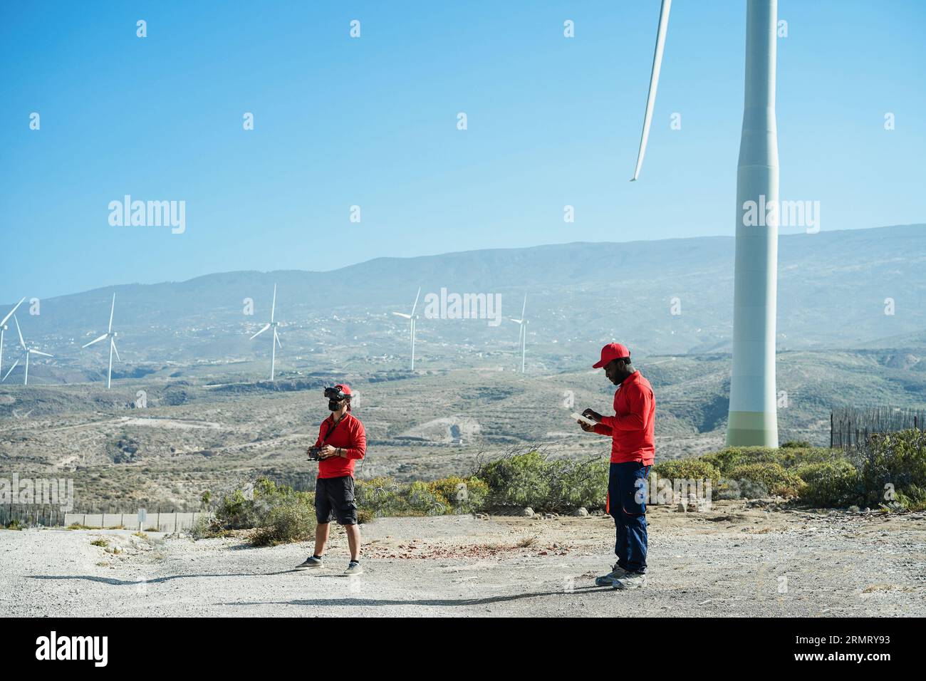 Engineers using virtual reality headset while working at windmill farm with tablet and drone - Renewable energy concept Stock Photo