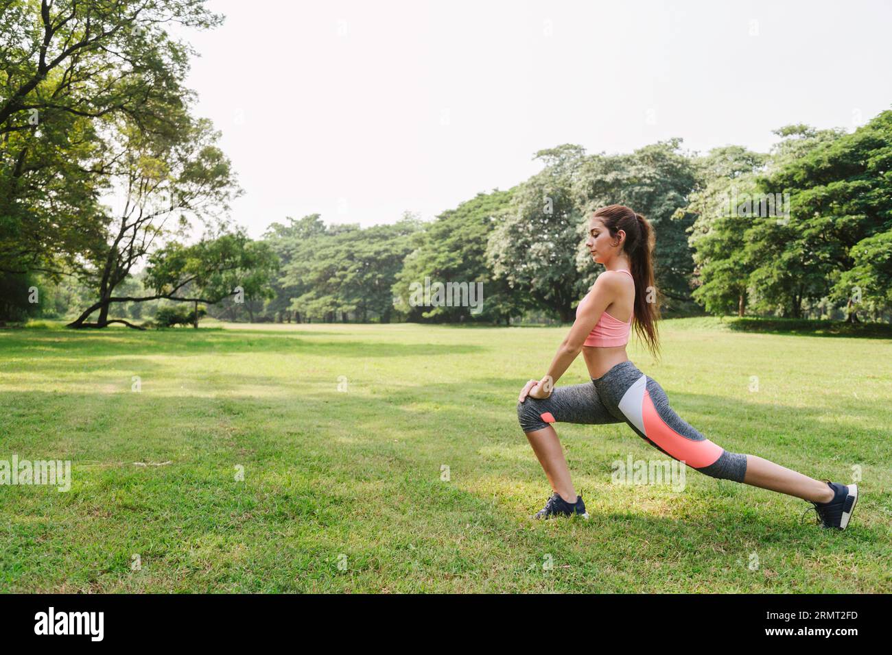 sports woman working out and stretching warm up leg muscle before outdoor running exercise in city park. outdoor fitness. Stock Photo