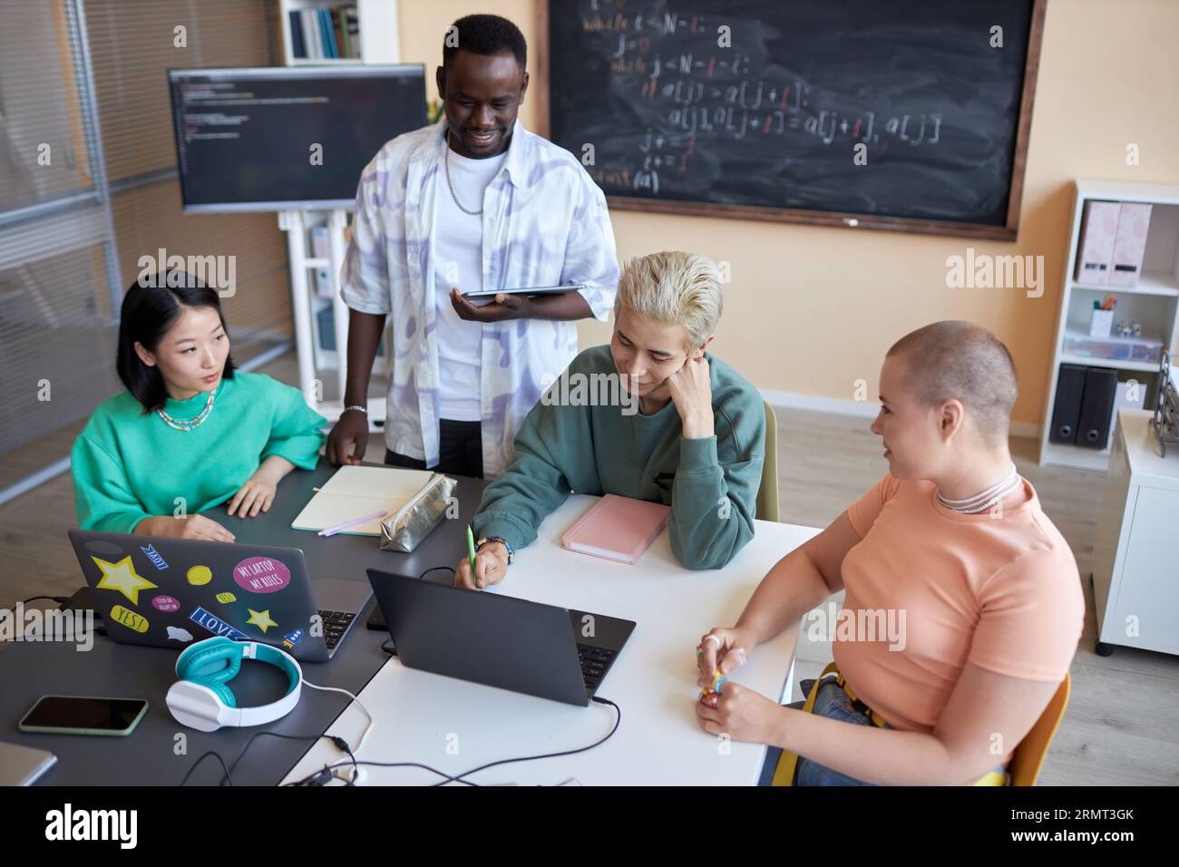 Team of highschool students brainstorming while preparing presentation of new project of decoding data or developing software at lesson Stock Photo