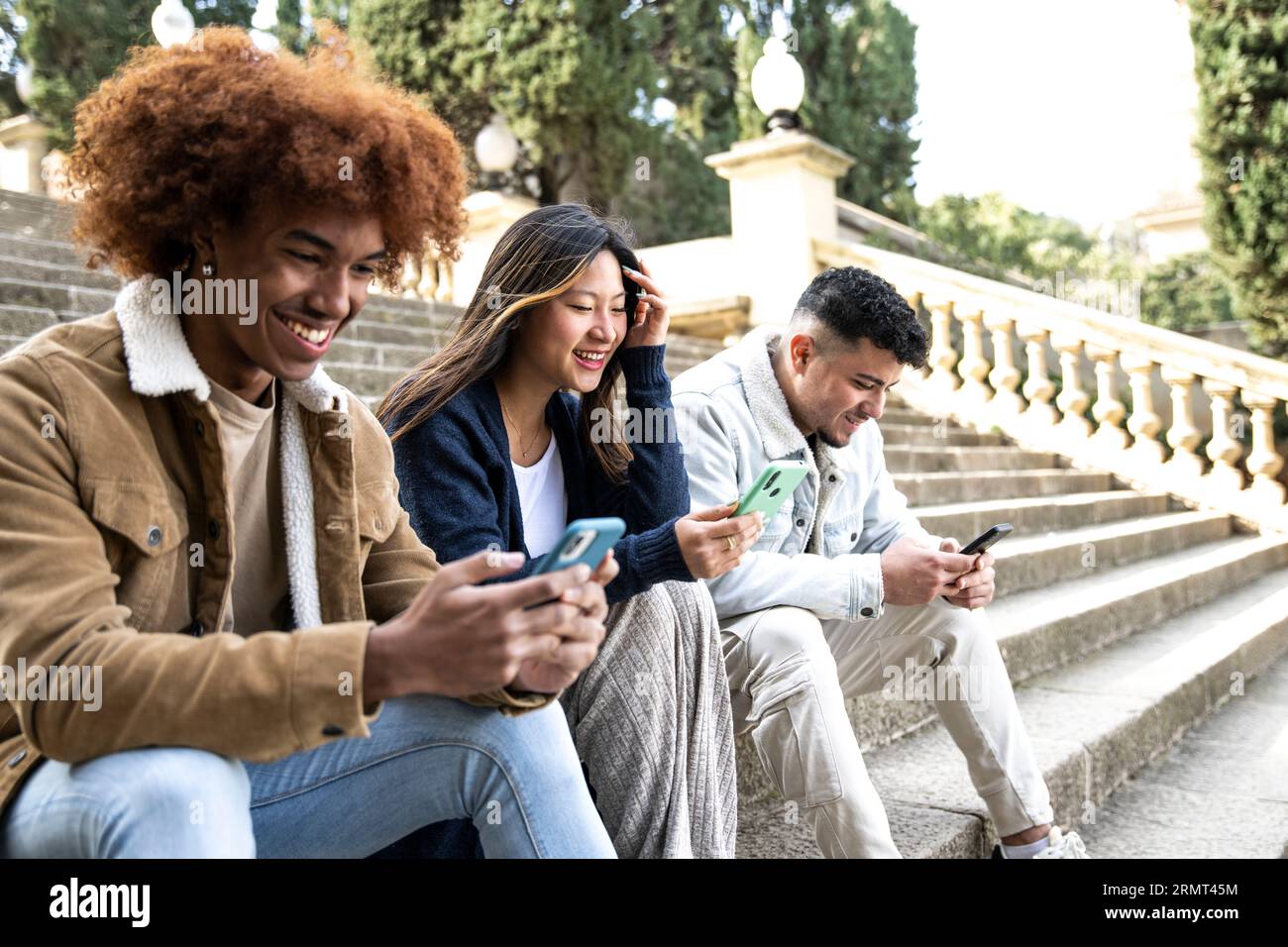 Three young diverse people texting with smartphones sitting on the ...