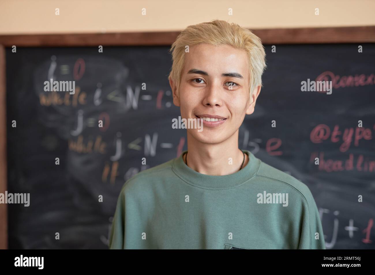 Happy Asian guy with dyed blond hair standing in front of camera