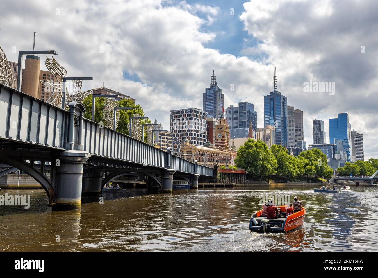 Melbourne, Australia - 22 Jan 2023: Bridge across the Yarra River, with people out on pleasure boat rides, and the modern city buildings beyond. Stock Photo