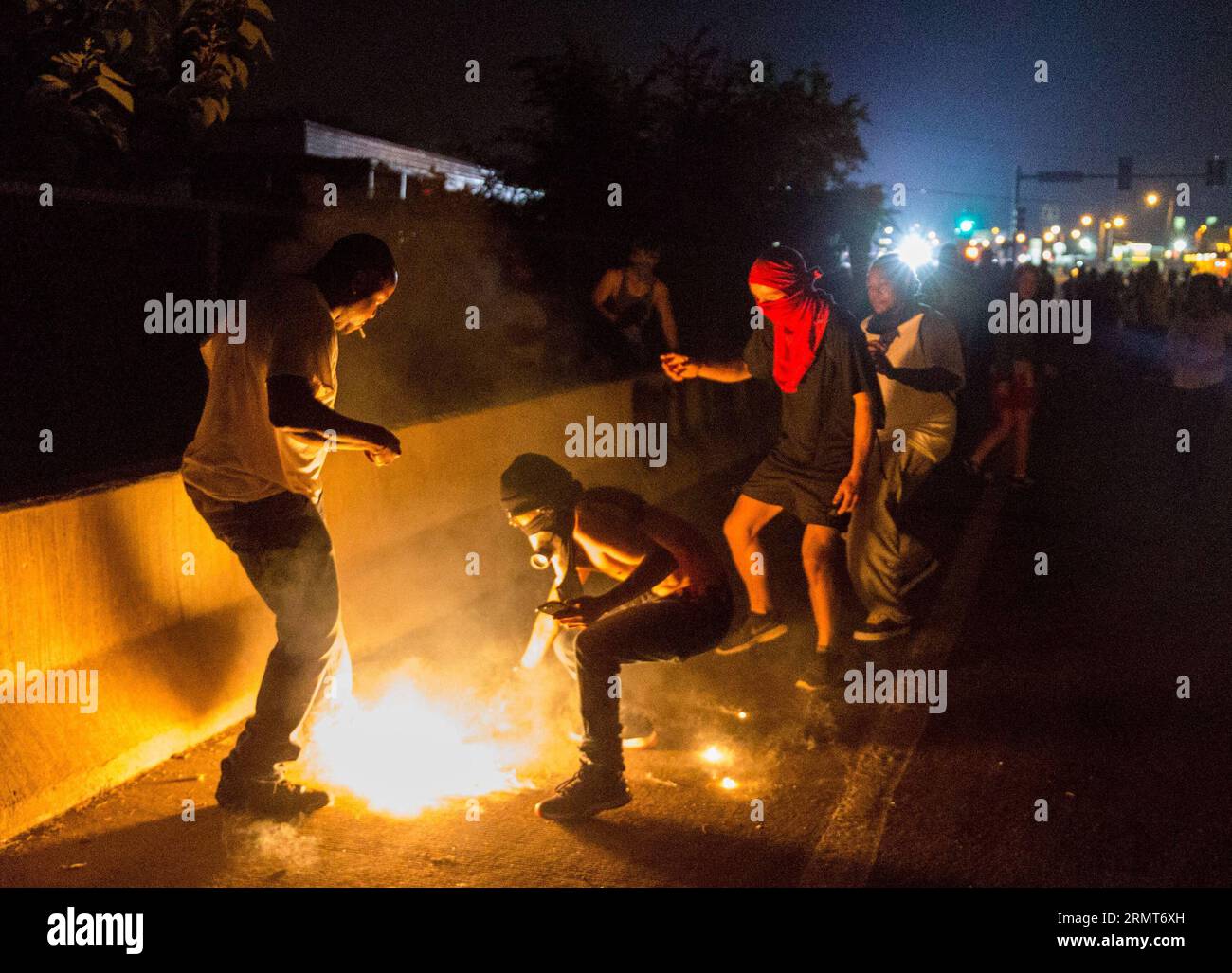 140819 -- FERGUSON, Aug. 19, 2014 -- A protestor picks up a teargas canister fired by the police during protests against police killing of Michael Brown in Ferguson, Missouri, the United States.18-year-old African American Michael Brown was shot dead by police in Ferguson, sparking continuous protests in the town where most of the population is black.  US-MISSOURI-FERGUSON-PROTEST-CLASH ShenxTing PUBLICATIONxNOTxINxCHN Stock Photo