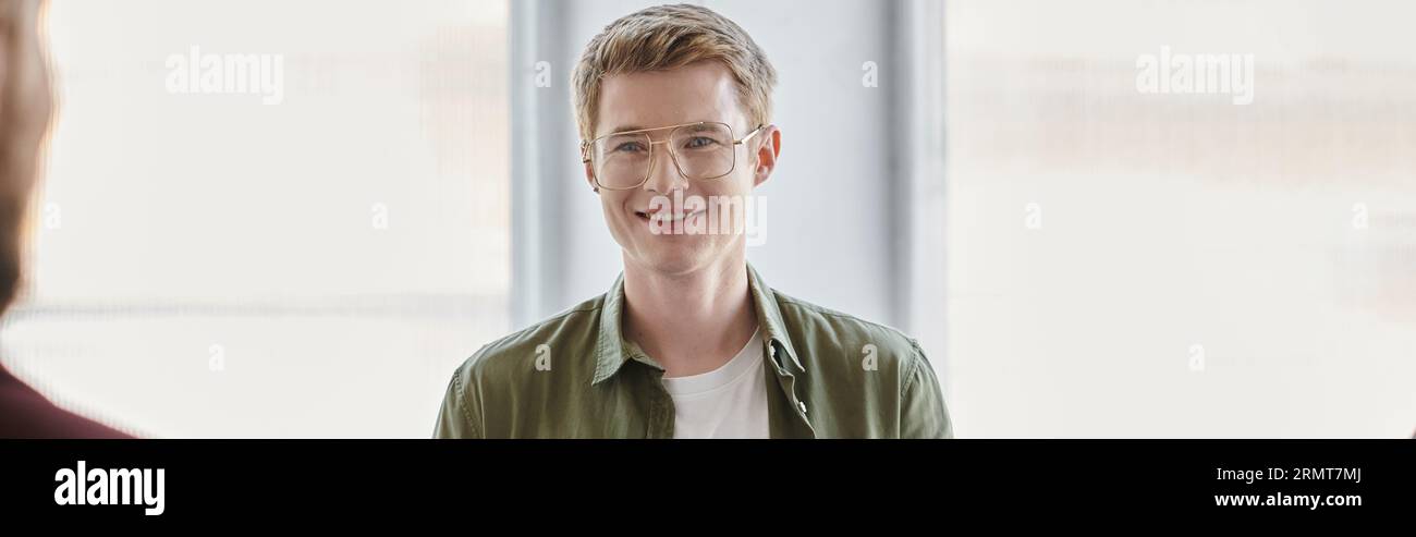 professional headshot of happy businessman in eyeglasses smiling in modern office, banner Stock Photo
