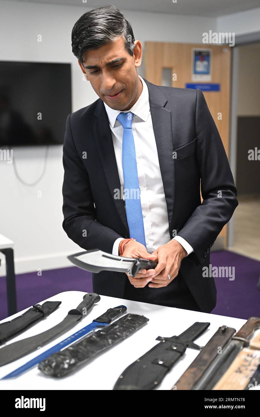 Prime Minister Rishi Sunak looks at knives and machetes seized from knife attacks during a visit