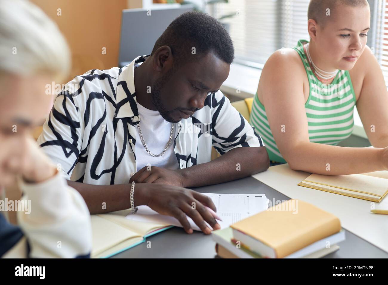 Serious African American guy looking through papers with test questions ...