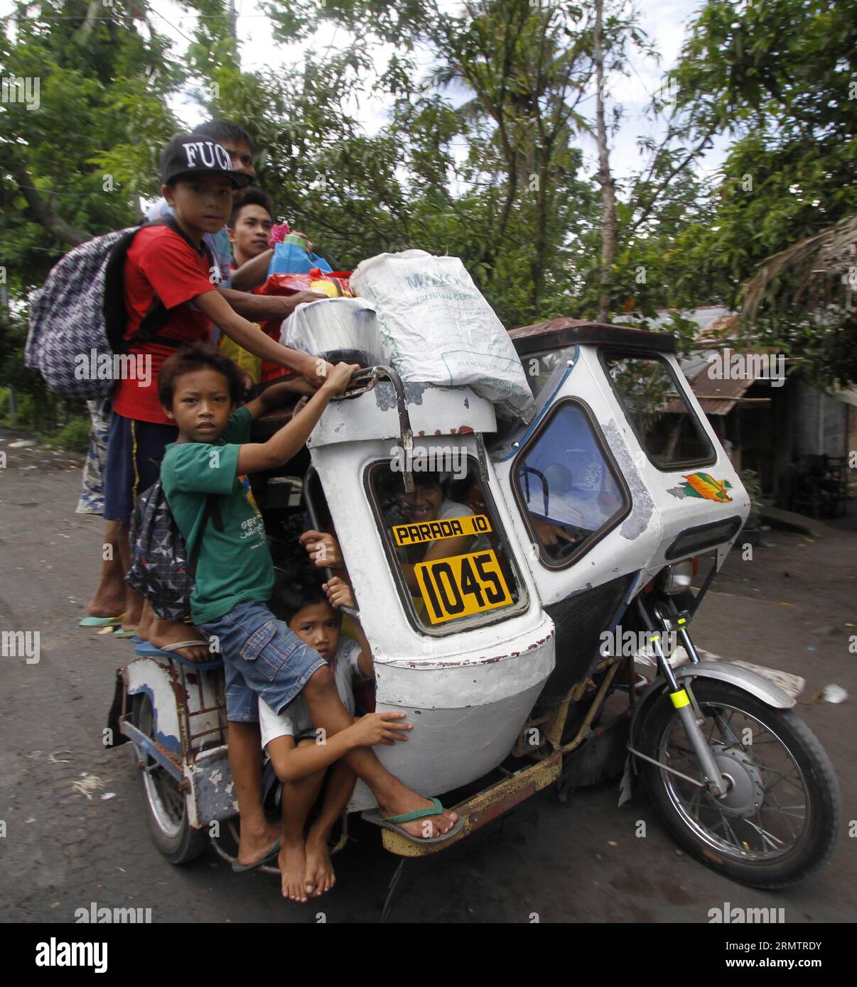 (140917) -- ALBAY, Sept. 17, 2014 -- Residents crowd on a tricycle as they evacuate from the danger zone near the Mayon Volcano in Albay Province, the Philippines, Sept. 17, 2014. The Philippine Institute of Volcanology and Seismology (PHIVOLCS) said Wednesday that Mayon Volcano in the eastern Philippine province of Albay has exhibited intense activity based on its 24-hour observation. The Philippine military said that more than 2,000 families or 10,000 individuals from five municipalities near the volcano have already been transferred to various evacuation centers. ) (zjy) PHILIPPINES-ALBAY-V Stock Photo