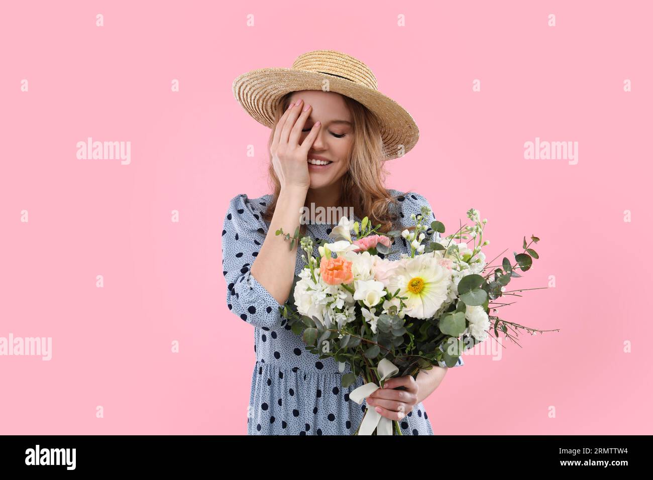 Beautiful woman in straw hat with bouquet of flowers on pink background ...