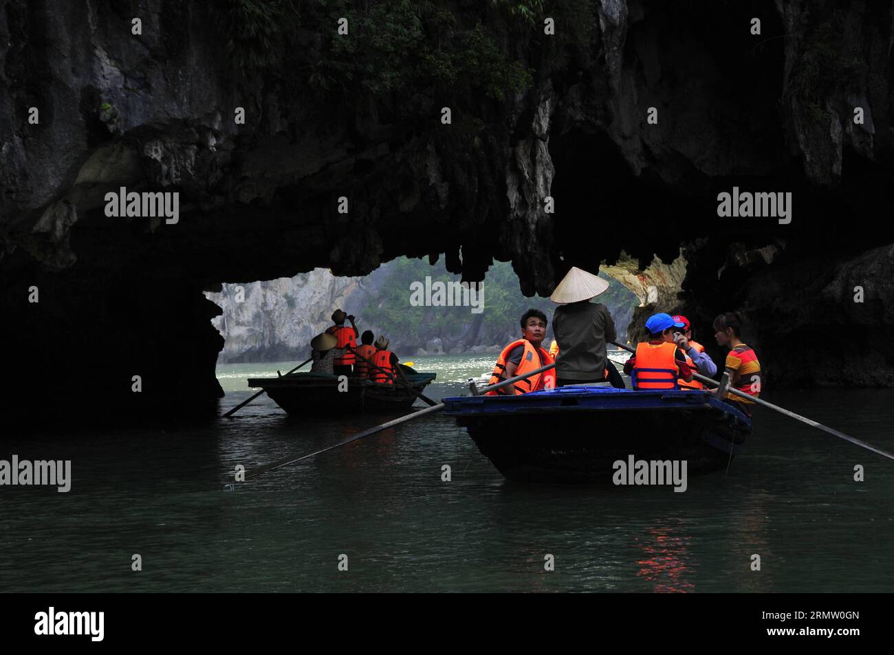(140925) -- HA LONG BAY, Sept. 24, 2014 -- Boats sail through archs at the bottom of the islands in Ha Long Bay, north Vietnam, Sept. 24, 2014. Ha Long Bay, in the Gulf of Tonkin, includes some 1,600 islands and islets, forming a spectacular seascape of limestone pillars. Because of their precipitous nature, most of the islands are uninhabited and unaffected by a human presence. The site s outstanding scenic beauty is complemented by its great biological interest. It was inscripted in UNESCO s World Natural Heritage list in 1994. ) VIETNAM-HA LONG BAY-WORLD HERITAGE ZhangxJianhua PUBLICATIONxN Stock Photo
