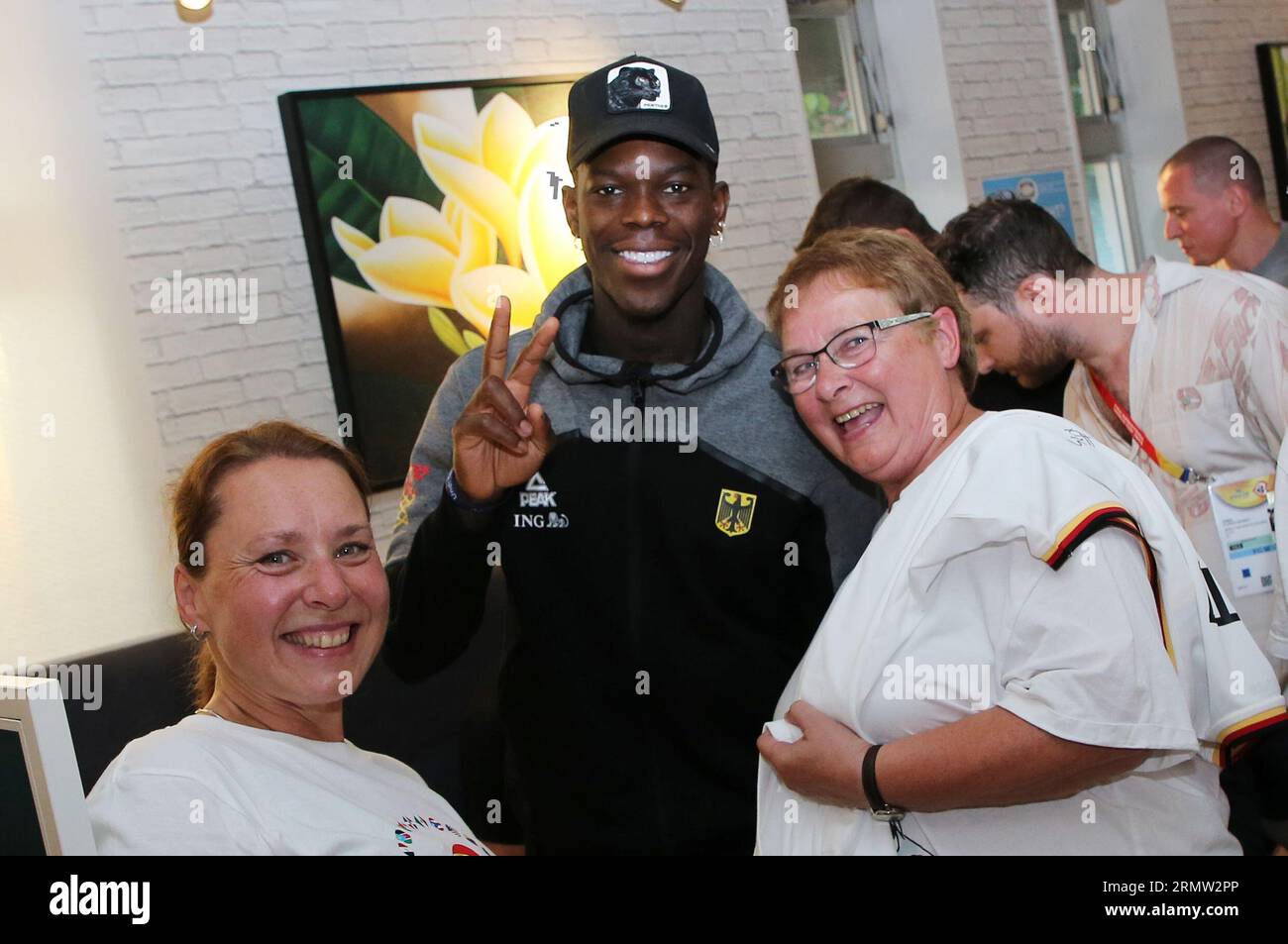 Okinawa, Japan. 30th Aug, 2023. Dennis Schröder (M) stands for a photo with two webish fans during a meeting of the German national basketball team with fans. The German basketball players enjoy a day off at the World Basketball Championships on Wednesday. Credit: Matthias Stickel/dpa/Alamy Live News Stock Photo