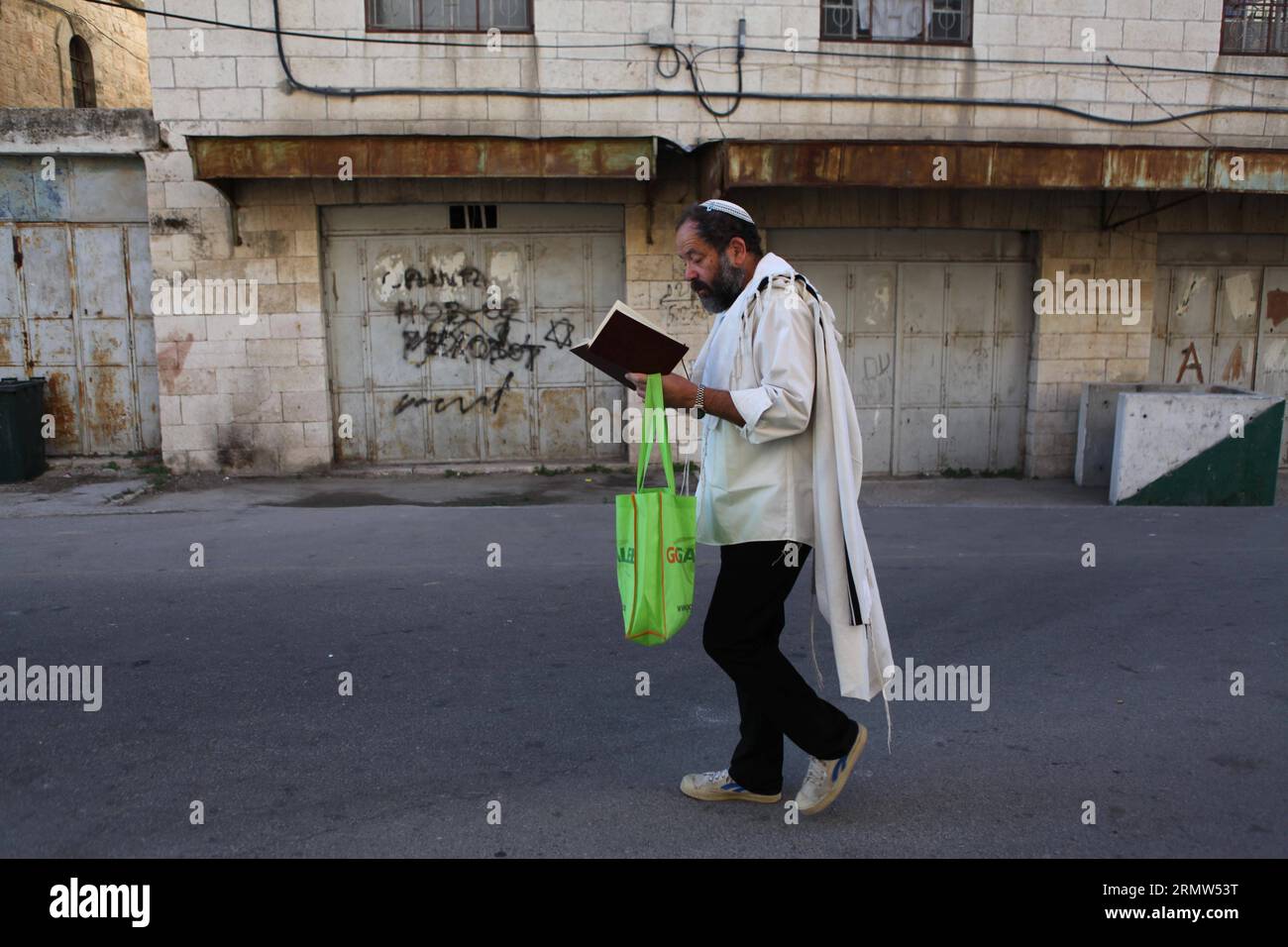(141004) -- HEBRON, Oct. 4, 2014 -- A Jewish worshiper walks near the al-Ibrahimi mosque, a religious site to Muslims, in the West Bank City of Hebron on Oct. 4, 2014. The Jewish fast of Yom Kippur is coinciding with the Muslim festival of Eid al-Adha for the first time in three decades. The concurrence of the holy days has not occurred for 33 years because the two faiths use different lunar calendars. ) MIDEAST-HEBRON-JEWISH-MUSLIMS MamounxWazwaz PUBLICATIONxNOTxINxCHN   Hebron OCT 4 2014 a Jewish worshiper Walks Near The Al Ibrahimi Mosque a Religious Site to Muslims in The WEST Bank City of Stock Photo