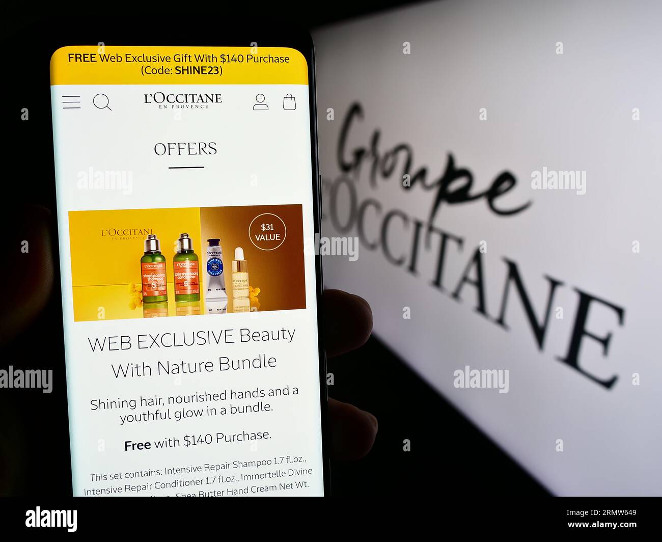 Person holding smartphone with web page of French cosmetics company Groupe L'Occitane on screen with logo. Focus on center of phone display. Stock Photo