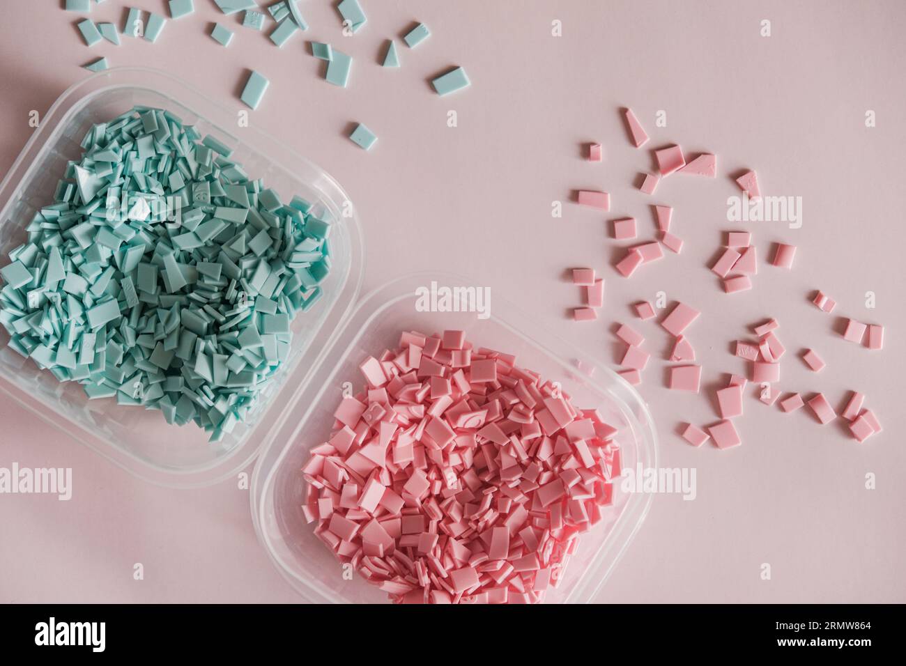 A pile of plastics - small pieces of hard plastic, pink and blue color, intended for further processing Stock Photo