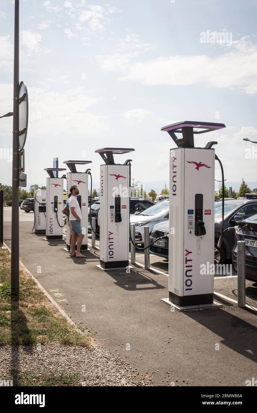 Two men watch while their Electric car charges at an Ionity charging ...
