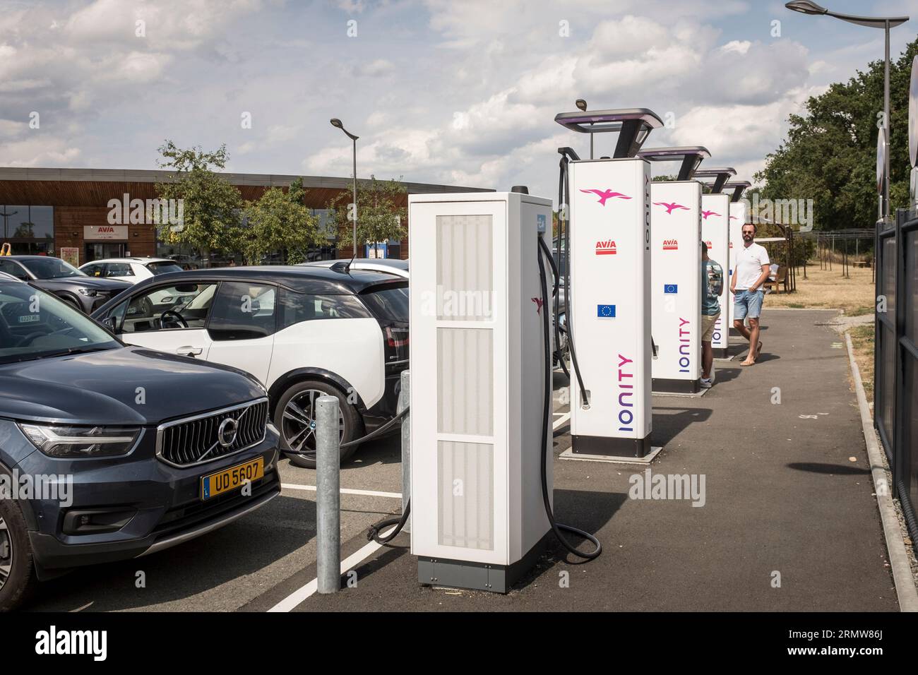 People wait while their Electric car charges at an Ionity charging ...