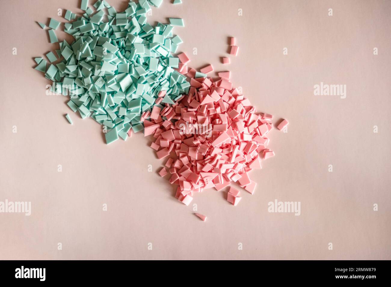 A pile of plastics - small pieces of hard plastic, pink and blue color, intended for further processing Stock Photo