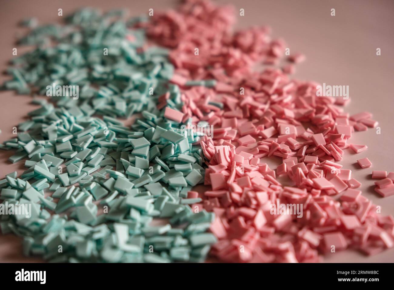 A pile of plastics - small pieces of hard plastic, pink and blue color, intended for further processing Stock Photo