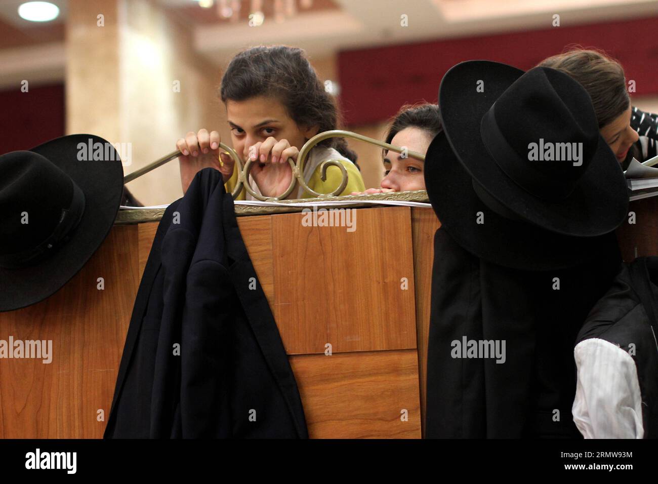 (141013) -- JERUSALEM, Oct. 13, 2014 -- Two Jewish girls peek Ultra-orthodox Jews dancing as they mark the ancient custom Simchat Beit Hashoeva in Bnei Brak near Tel Aviv on Oct. 13, 2014. Simchat Beit Hashoeva or the joy of drawing is a commemoration and fulfilment of the Muitzvah to rejoice during the week-long holiday of Sukkot which started last Wednesday.) ISRAEL-JERUSALEM-UNTRA ORTHODOX-DANCE-SUKKOT GilxCohen PUBLICATIONxNOTxINxCHN   Jerusalem OCT 13 2014 Two Jewish Girls Peek Ultra Orthodox Jews Dancing As They Mark The Ancient Custom Simchat Beit  in  Brak Near Tel Aviv ON OCT 13 2014 Stock Photo