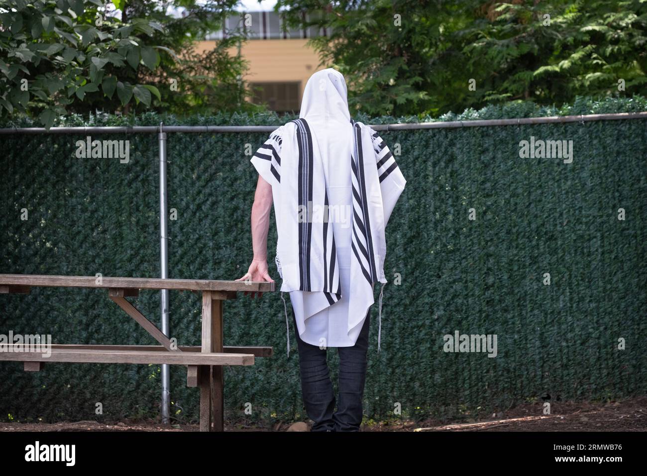 An orthodox Jewish man photographed from behind, reciting morning