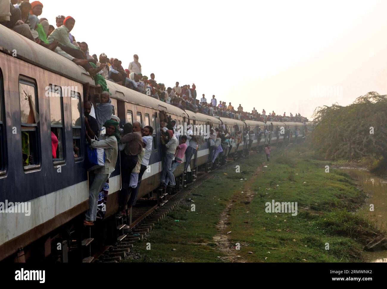 (141106) -- PATNA,  Nov. 6, 2014 -- Photo taken on Nov. 6, 2014 shows an overcrowded passenger train passing through Patna city, India. The train is overcrowded because people are coming to have a dip in the holy river Ganga for Kartik Purnima festival. Devotees sail fancy boats carrying earthen lamps, coins and flowers to celebrate Kartik Purnima festival on the end day of the holy month Kartik. )(bxq) INDIA-PATNA-OVERCROWDED TRAIN-KARTIK PURNIMA FESTIVAL Stringer PUBLICATIONxNOTxINxCHN   Patna Nov 6 2014 Photo Taken ON Nov 6 2014 Shows to Overcrowded Passenger Train passing Through Patna Cit Stock Photo