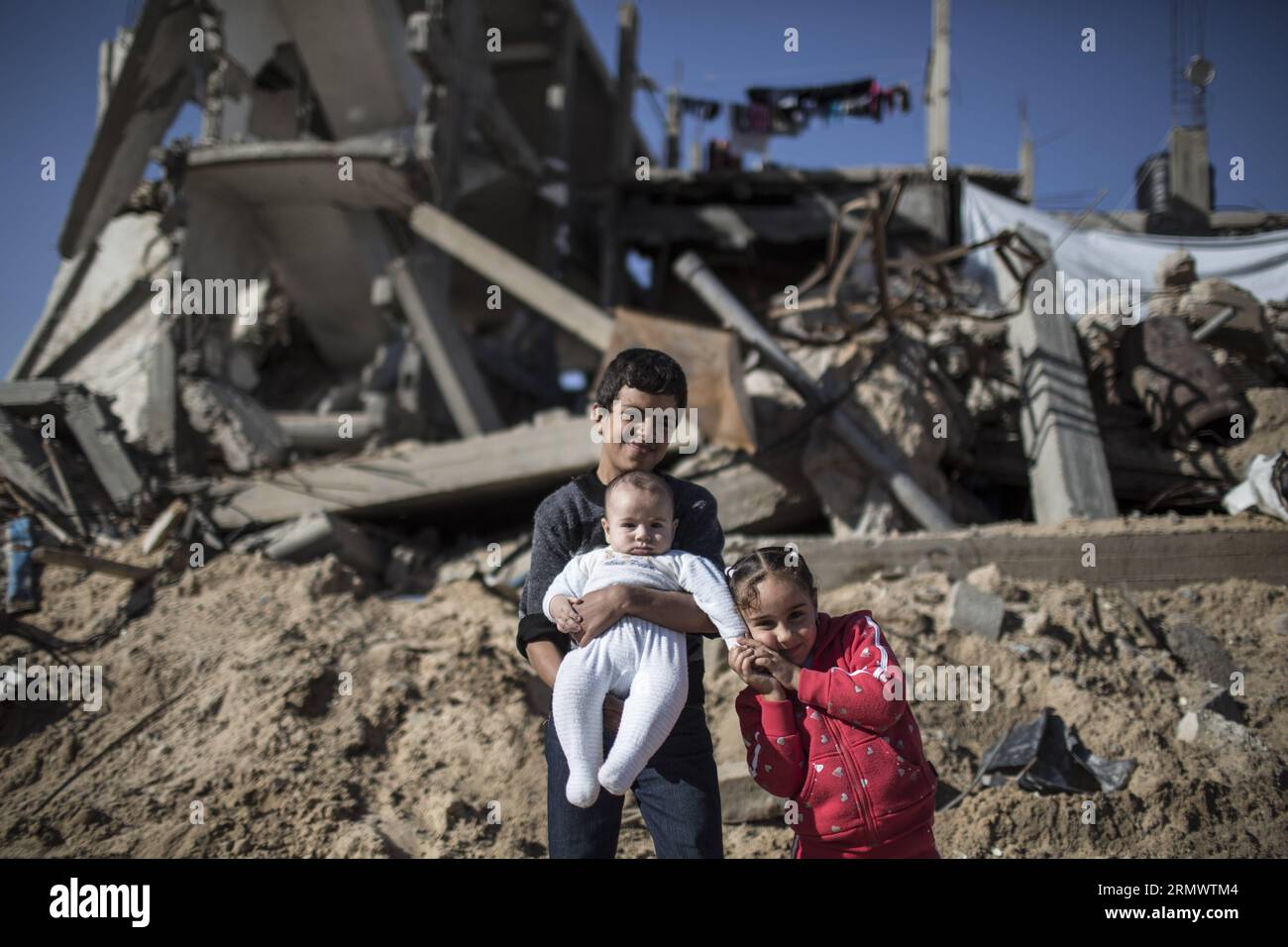 Palestinian Yousef Saudi, 12, his sister Roaa Saudi, 6, and their youngest  brother Uday Saudi, 4 months are seen near the rubble of their destroyed  house in Al-Shejaiya neighborhood, east of Gaza