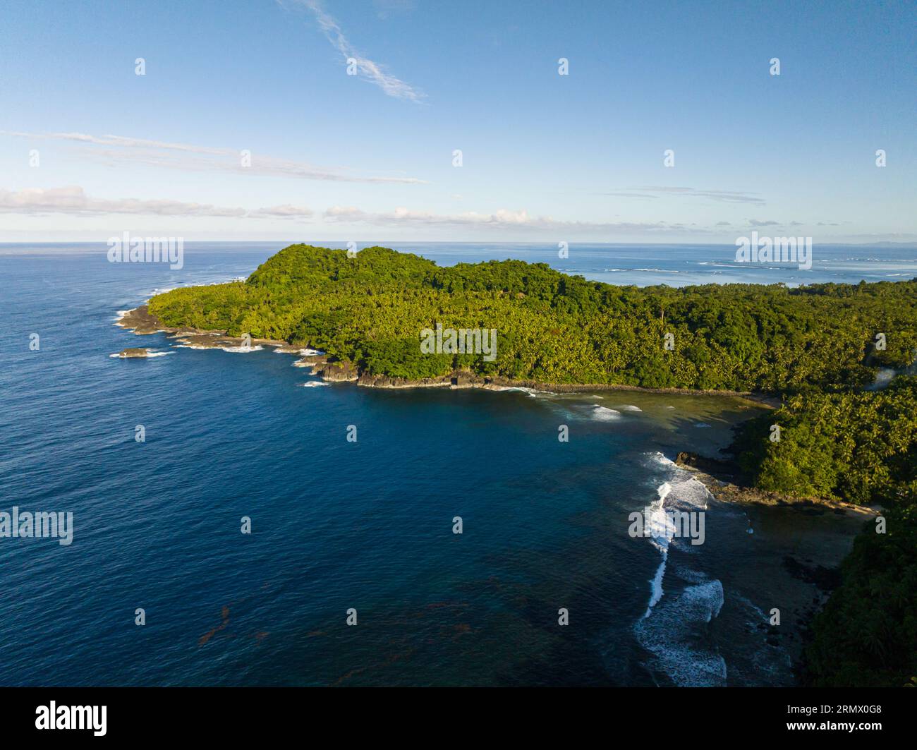 Rocky coastline of Tropical Island surrounded by deep blue sea with a great view of skyline. Surigao del Sur. Mindanao, Philippines. Stock Photo