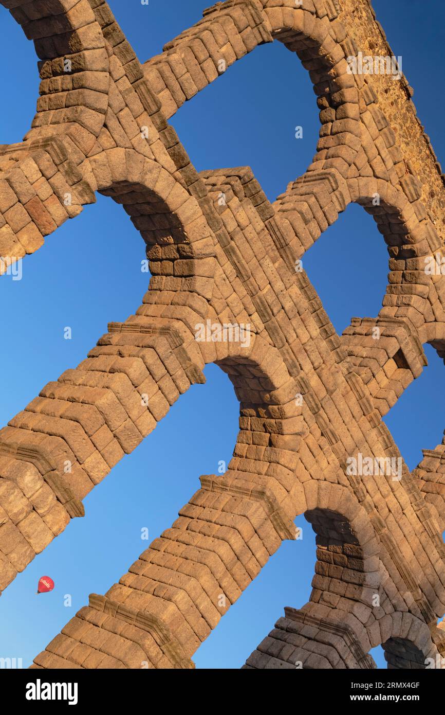 Spain, Castile and Leon, Segovia, Hot air balloon gliding past as early morning golden light shines on the Aqueduct of Segovia, a Roman aqueduct with Stock Photo