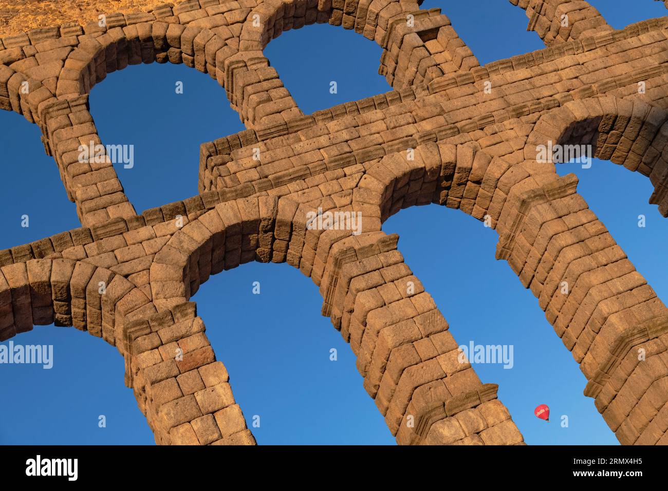 Spain, Castile and Leon, Segovia, Hot air balloon gliding past as early morning golden light shines on the Aqueduct of Segovia, a Roman aqueduct with Stock Photo